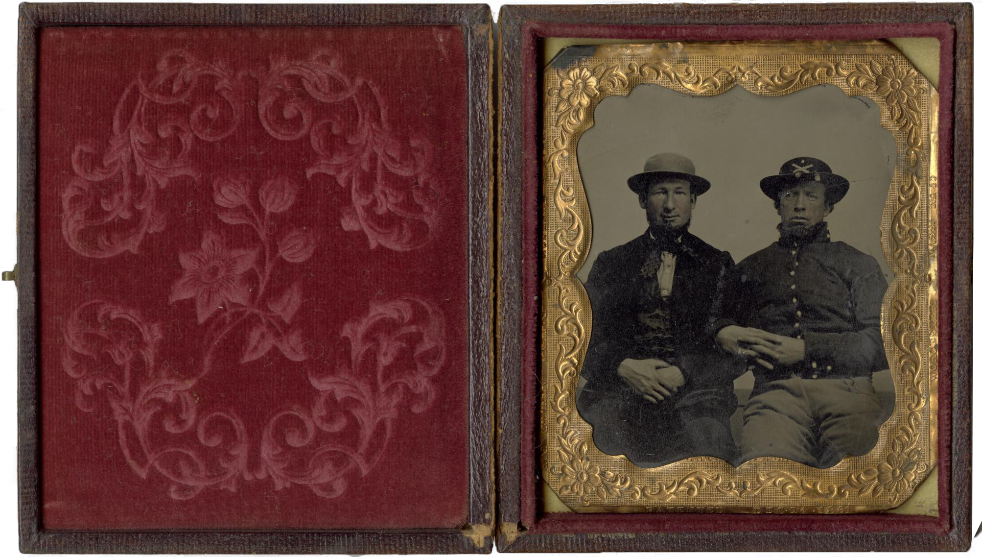 Soldier and Friend Tintype portrait of a Union soldier and a friend. Three quarter length portrait of two seated men, both bearded, with arms linked. Man on left wears a round hat and civilian clothes; the man on the right wears a Union soldier's uniform, including hat with crossed rifle insignia.