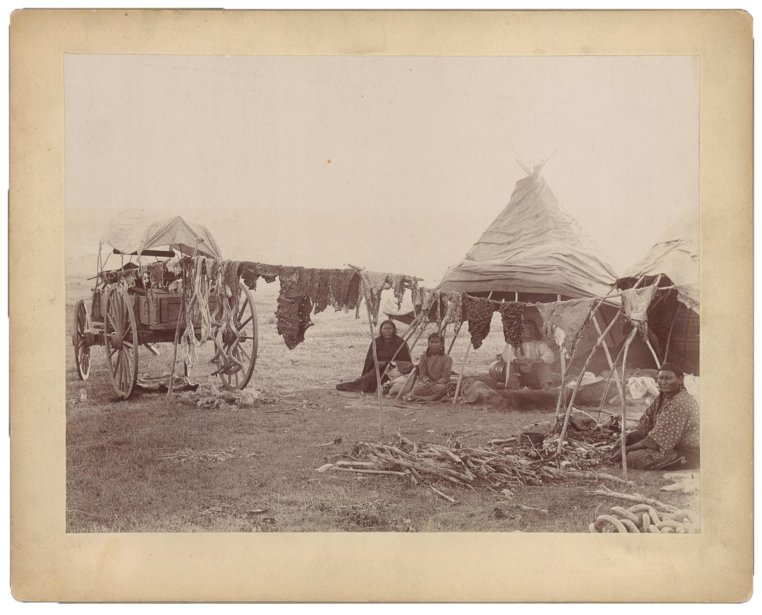 pohrt_759_MED062_001_med062_001_1544x1431 Group portrait of unidentified family of Northern Cheyenne Indians (three women and one man) at an encampment on Northern Cheyenne Indian Reservation near Lame Deer, Montana, with makeshift tents, wagon and drying racks of beef meat including intestines.